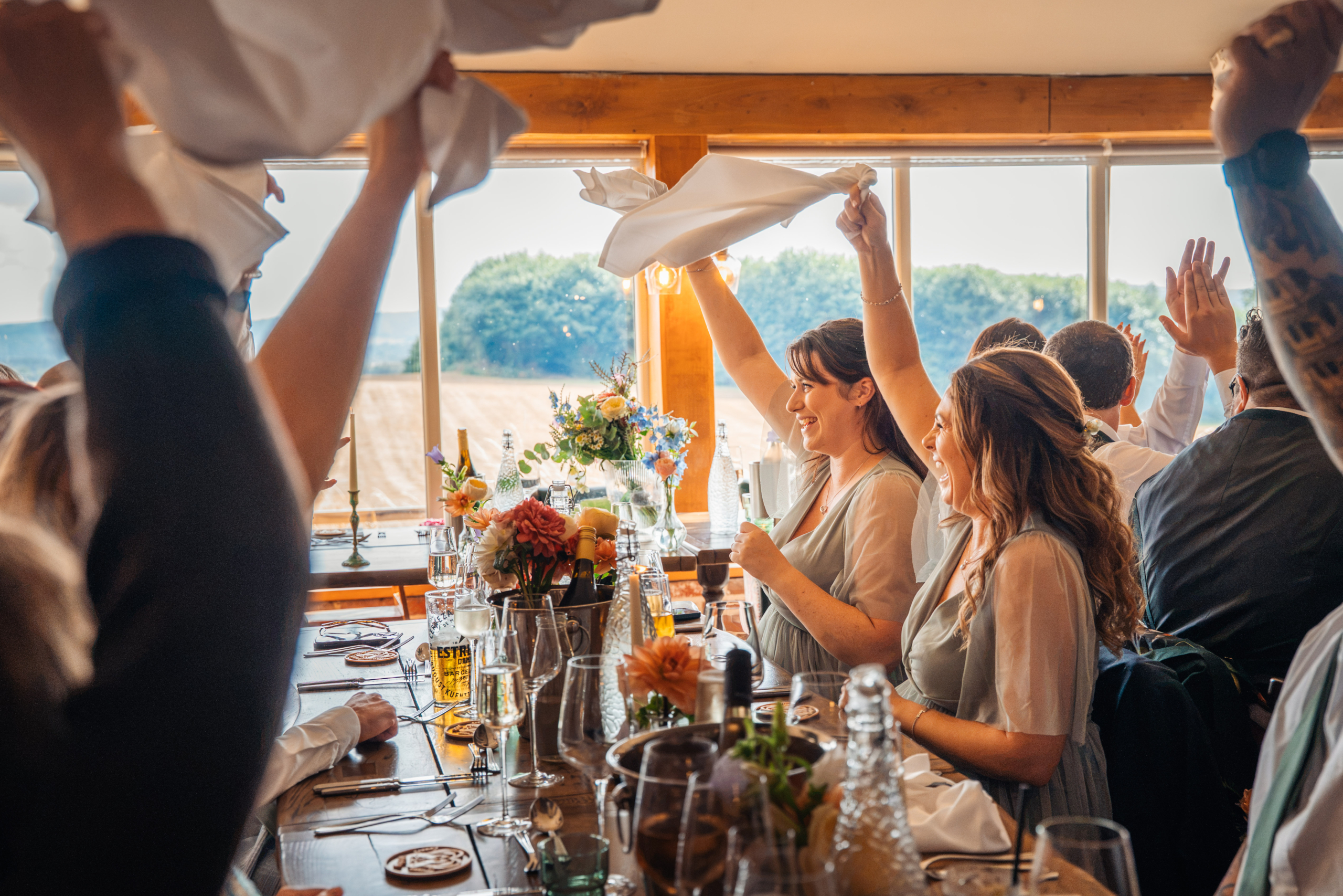 Guests raising their glasses at a long table, featured in our guide to Father of the Bride Speech Tips