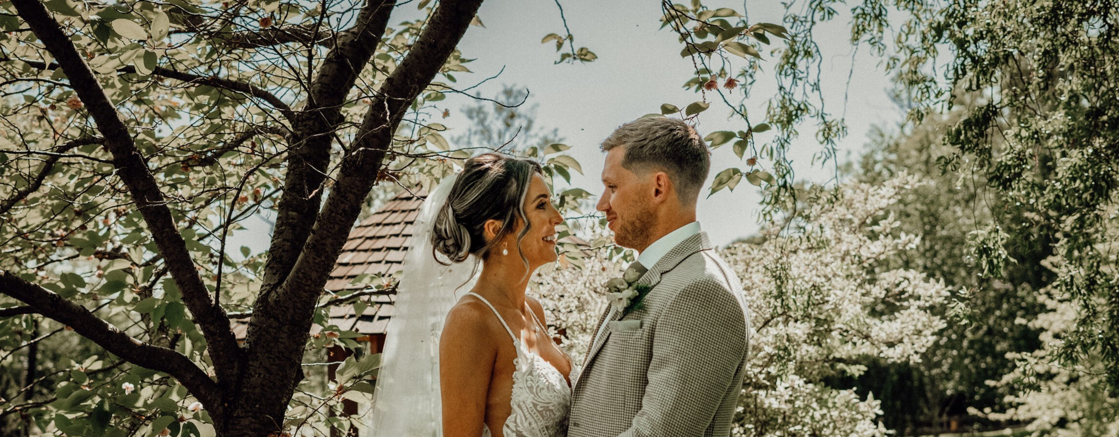 Bride and groom facing each other beneath blossom, an emotional first look wedding moment