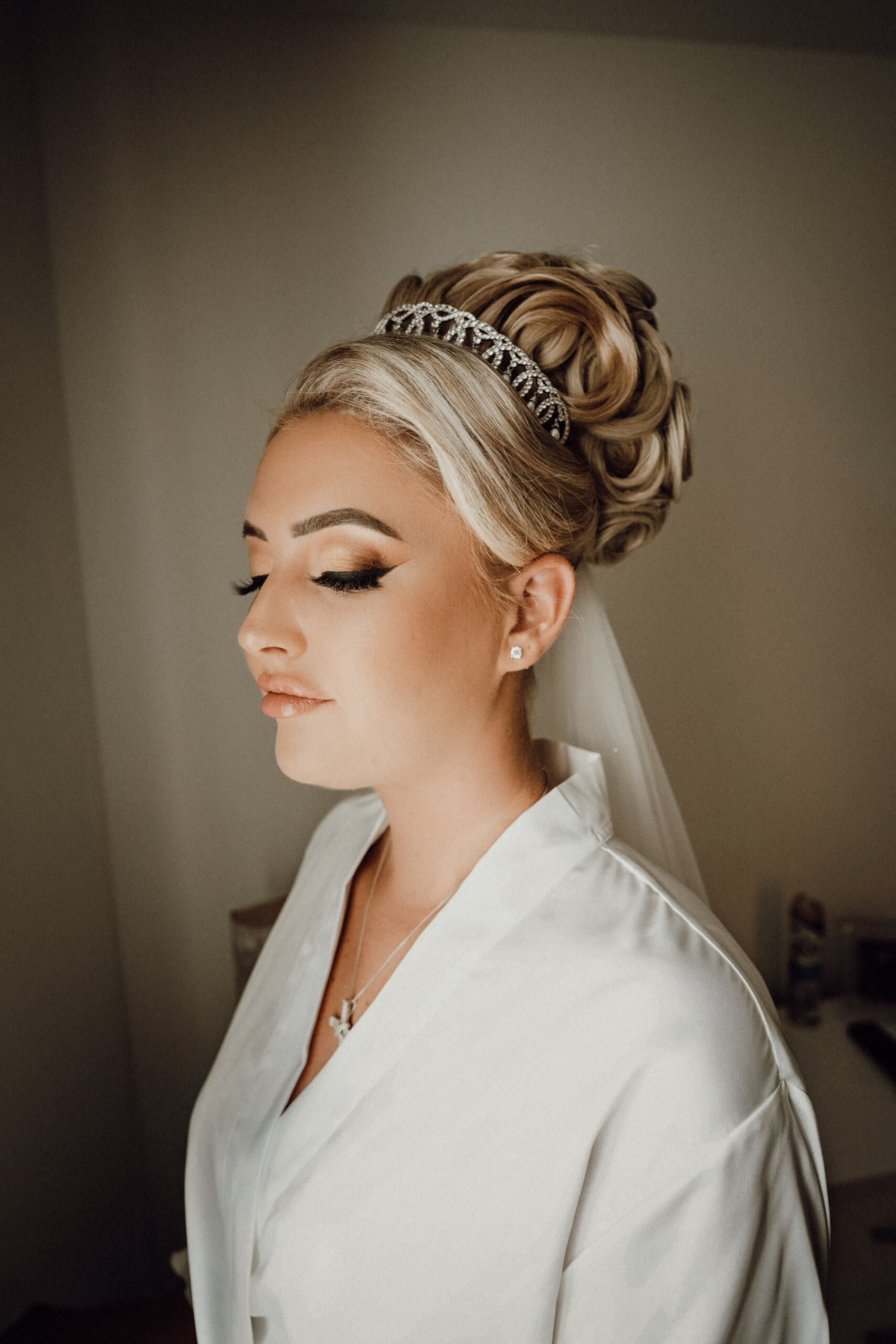 Bride having her make-up finished on the wedding morning, part of a set of getting ready wedding photos