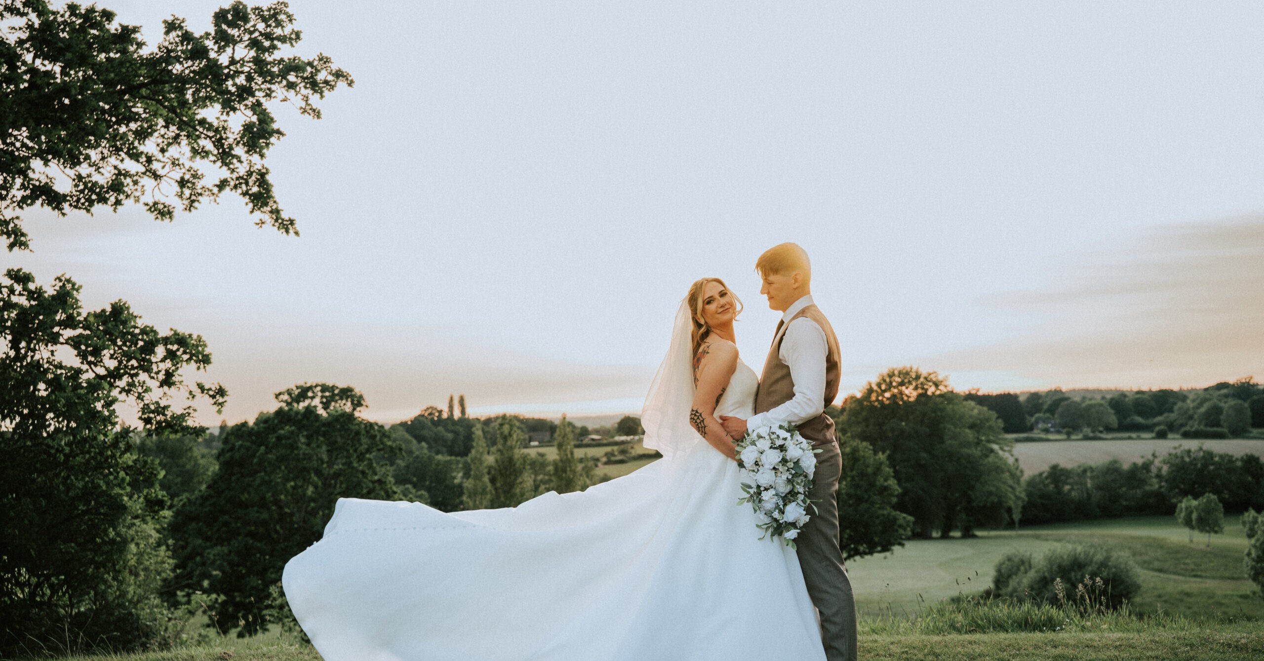 Bride lifting her dress in soft evening sun, one of a set of golden hour wedding photos