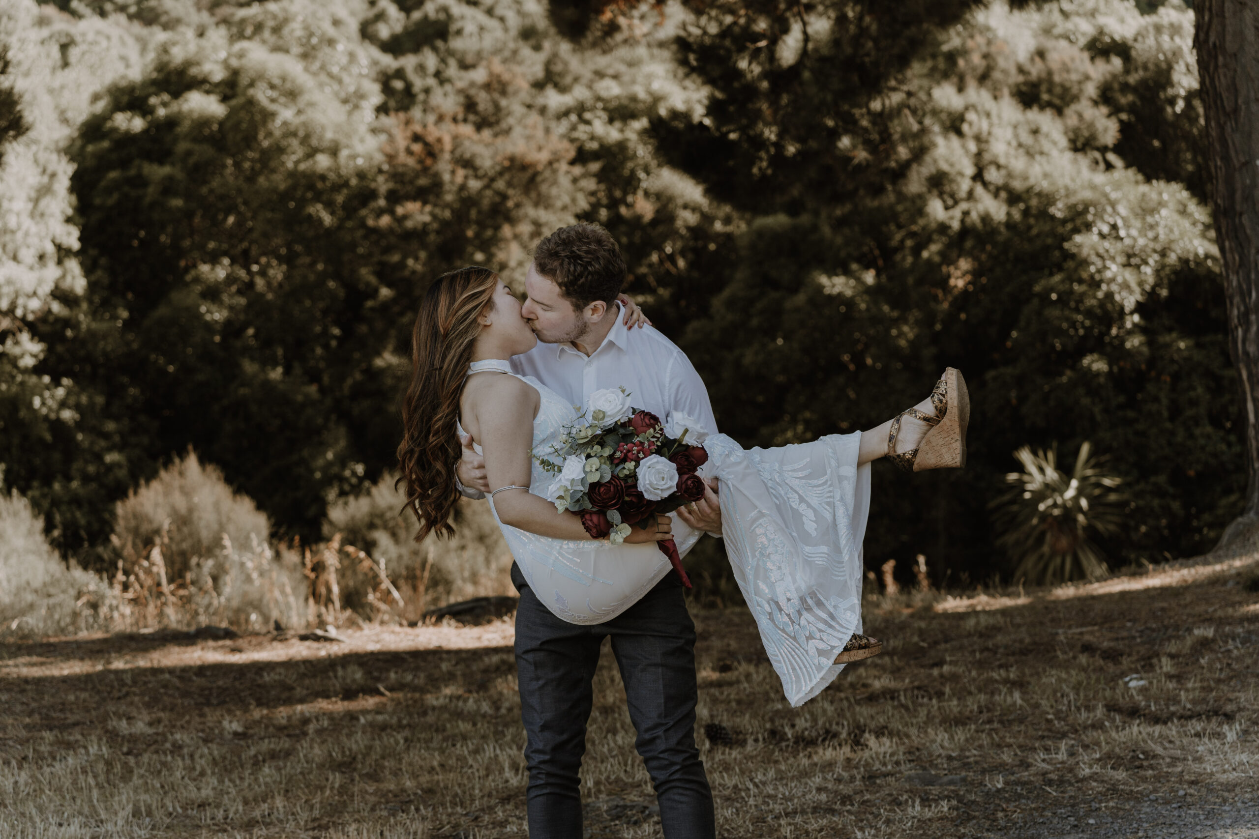 Groom lifting the bride on a woodland path, a relaxed pre wedding photoshoot in the woods