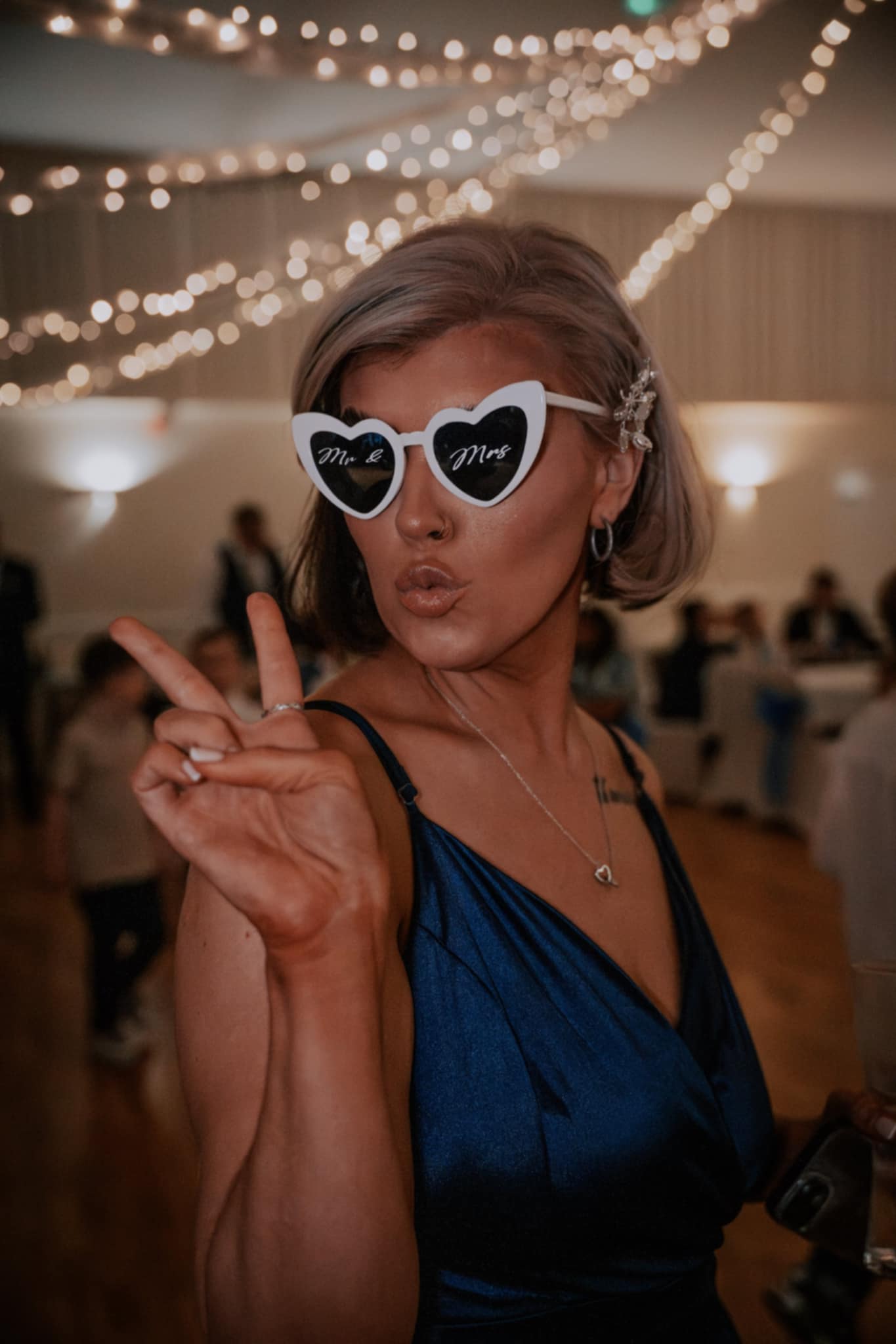 Wedding guest posing in heart sunglasses, the candid fun a wedding content creator films for social media