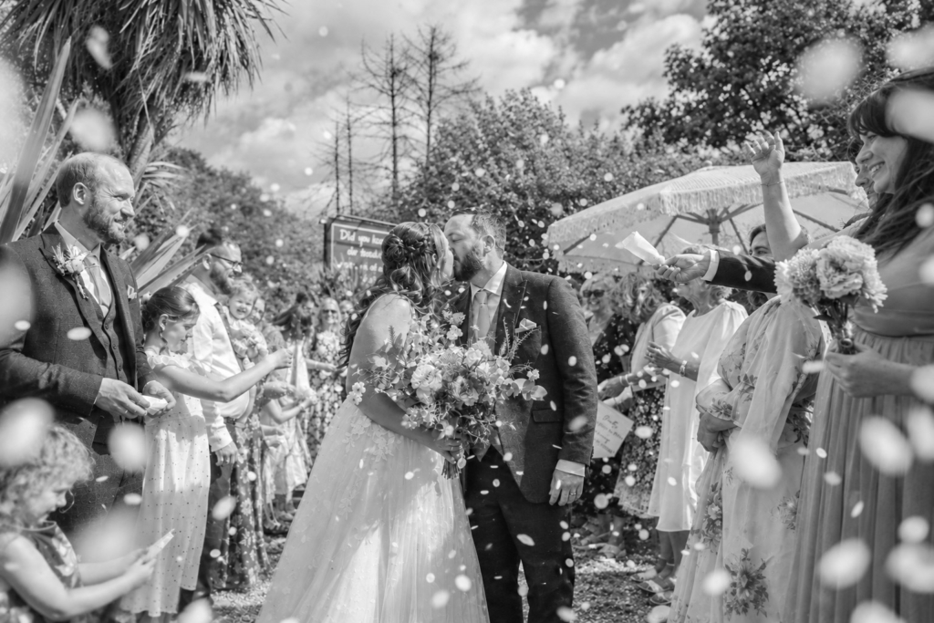 Black and white photo of guests throwing confetti, a candid moment ideal for wedding instagram content