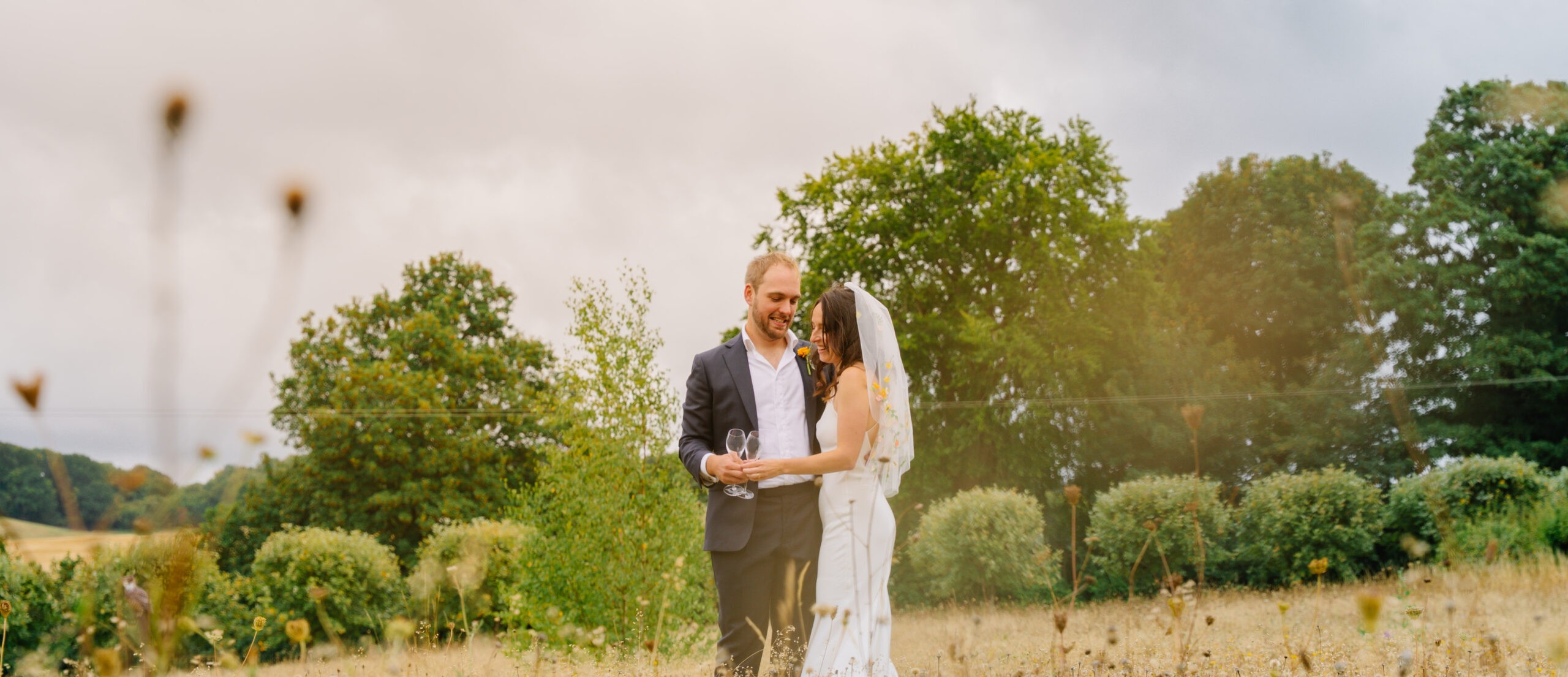 Bride and groom among trees in a meadow, wedding stationery and details secured with a wedding photographer deposit