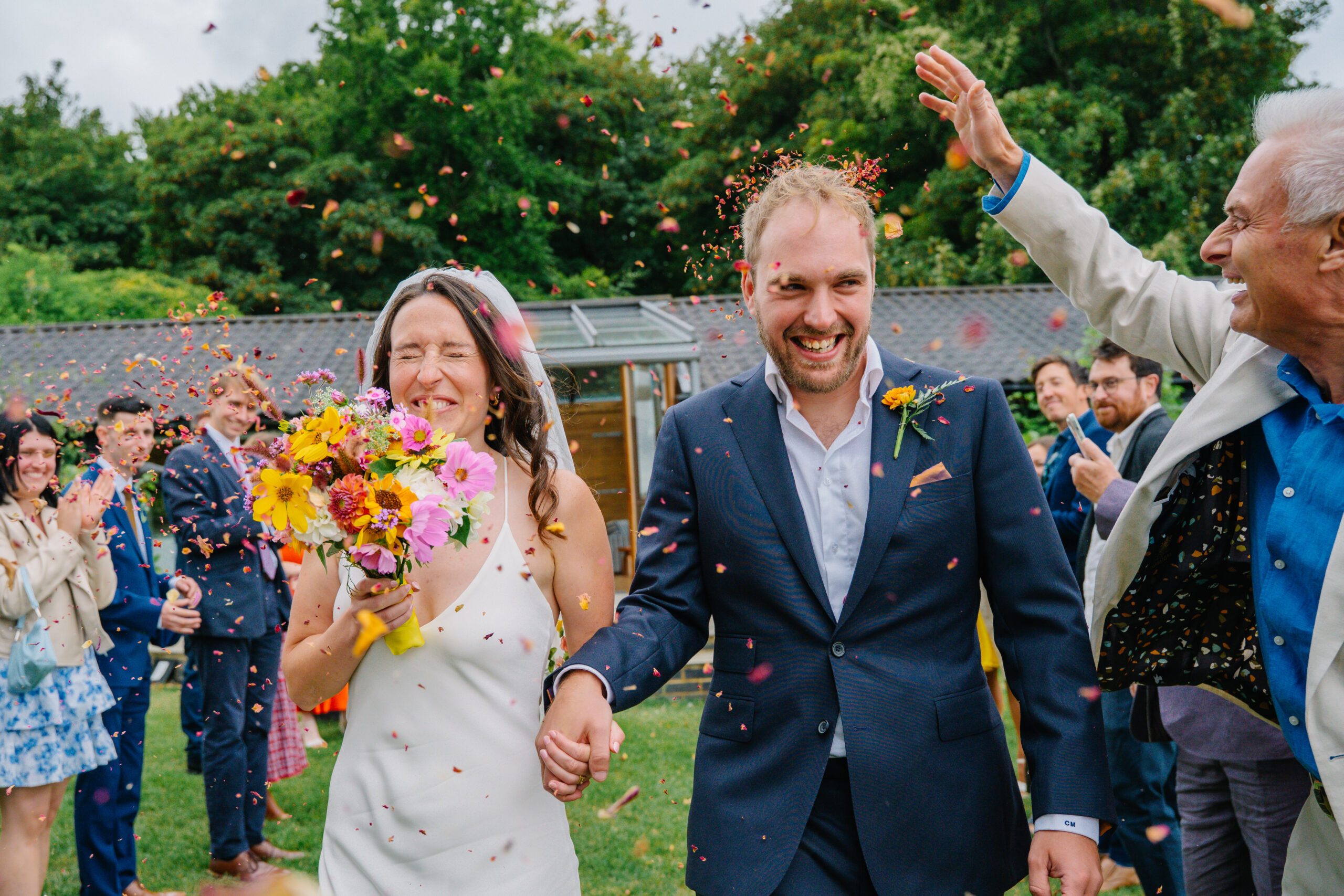 Bride and groom walking out to cheering guests, captured by a wedding photographer in Bursledon