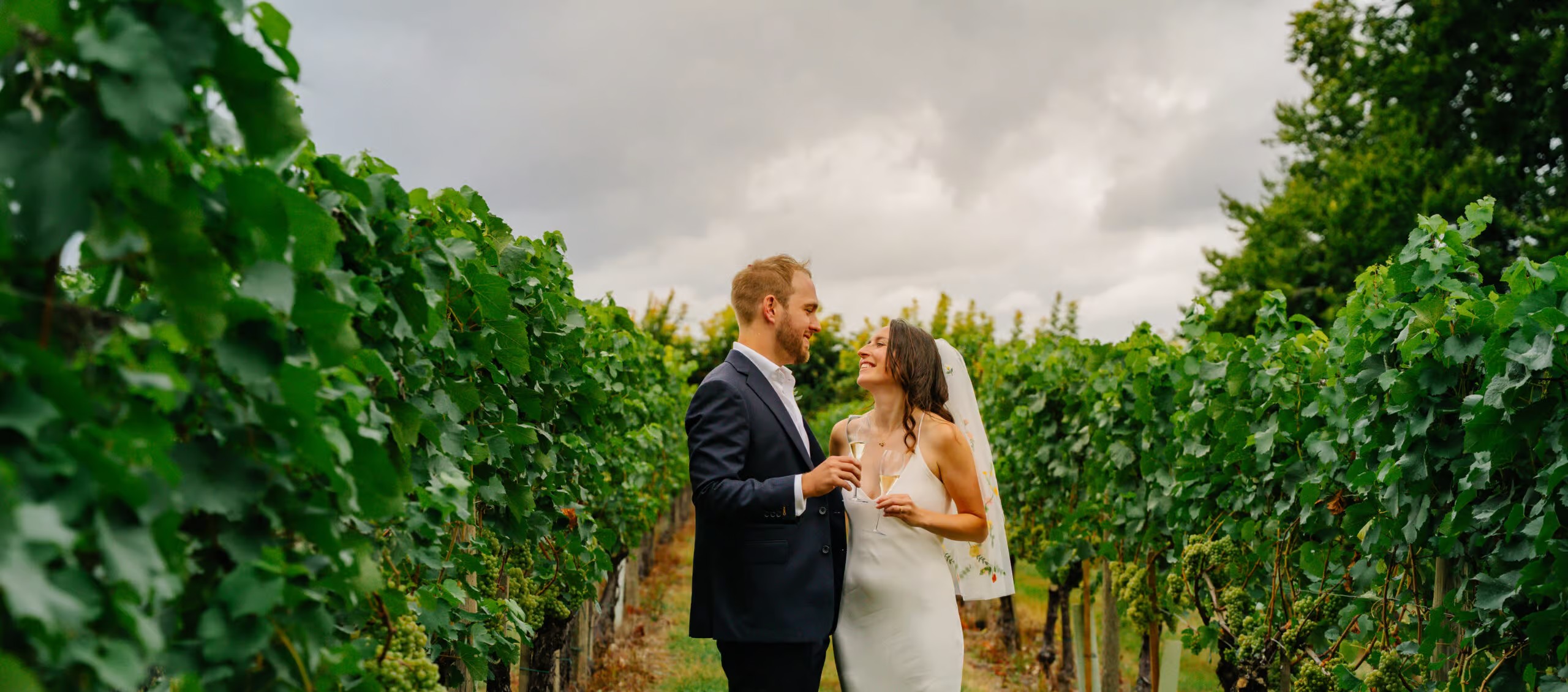 Bride and groom walking between rows of vines, a result of following simple wedding photography tips