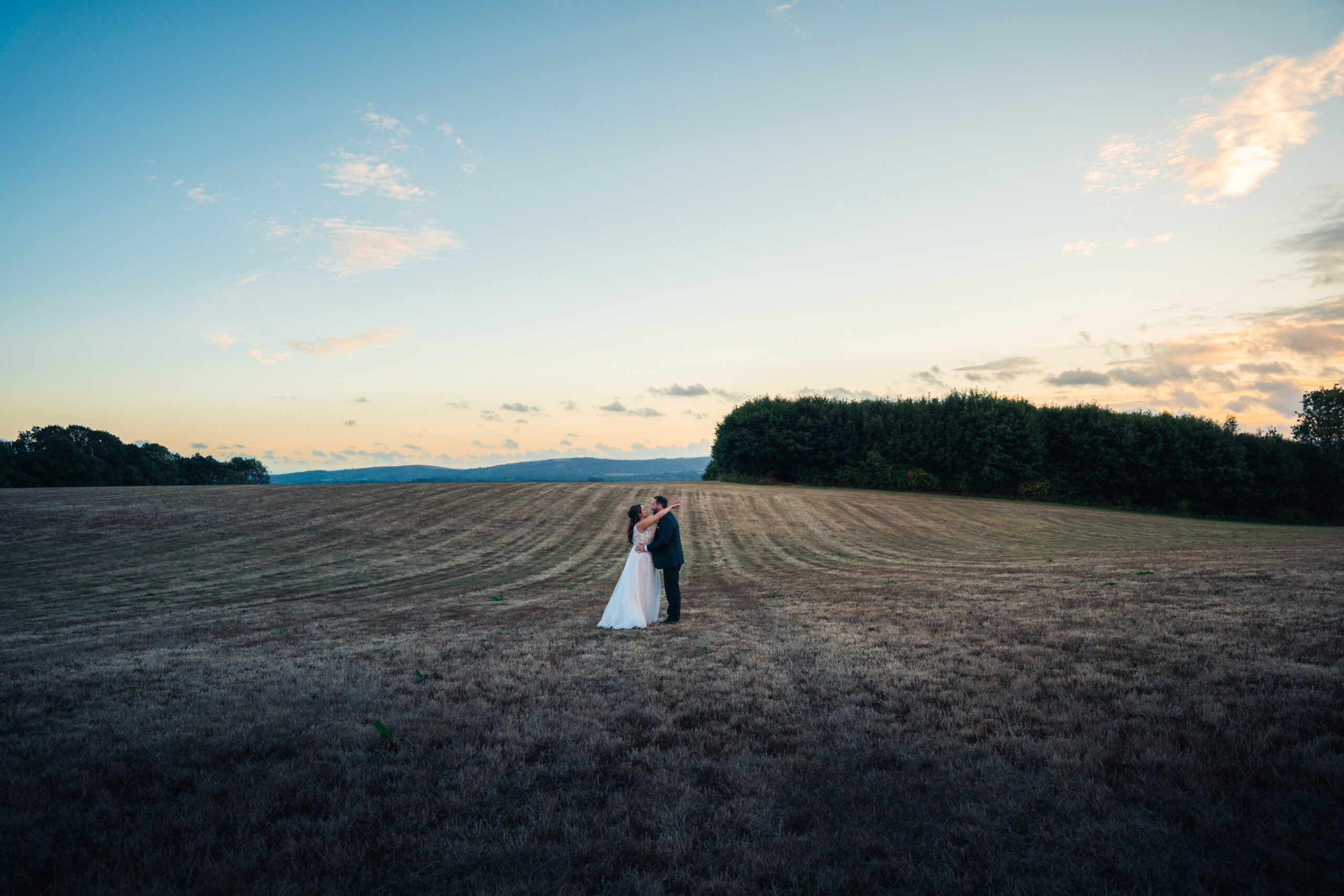A couple in a wide open field at golden hour in Hampshire